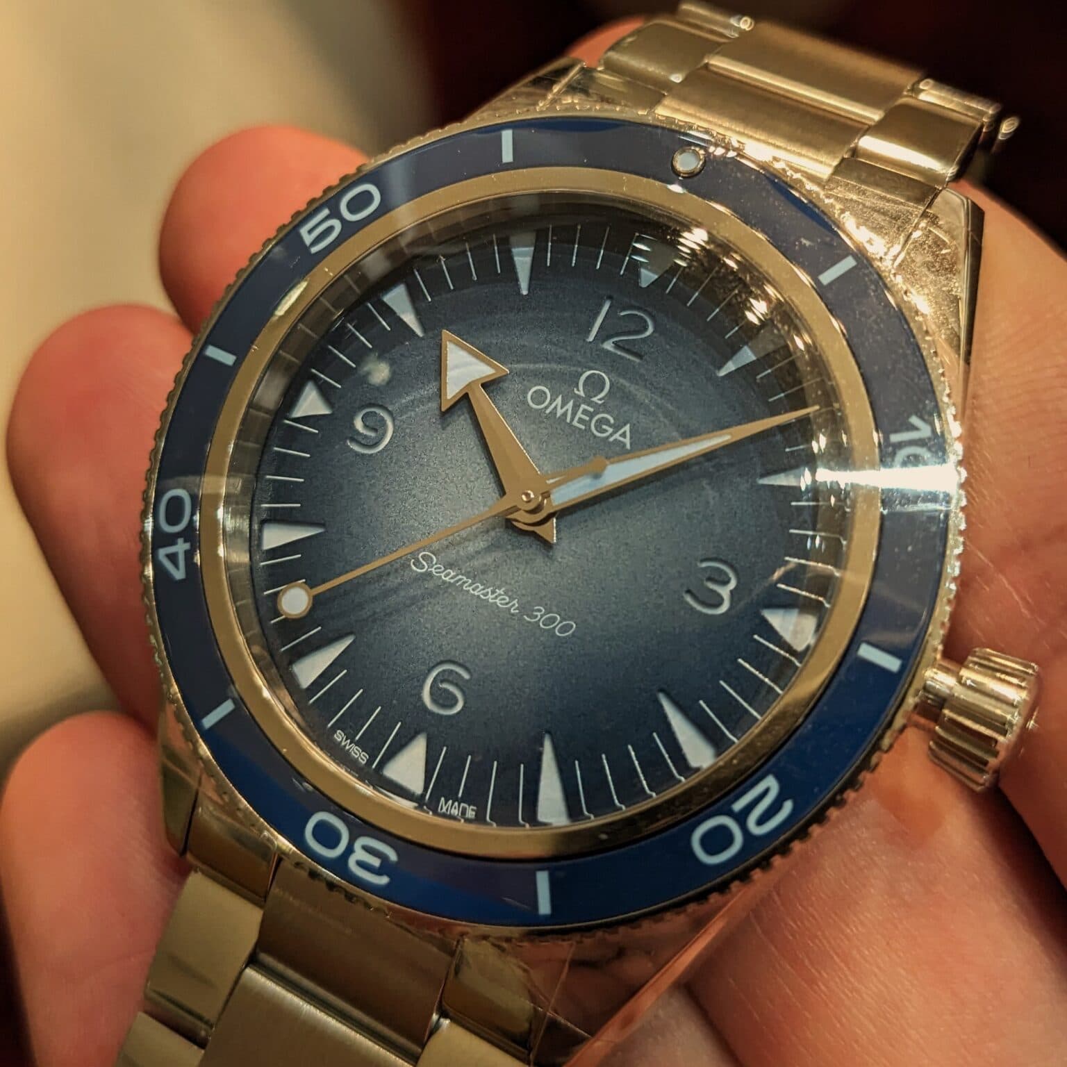 blue watch with a gradual light blue dial and blue bezel with arrow hands and steel case and bracelet