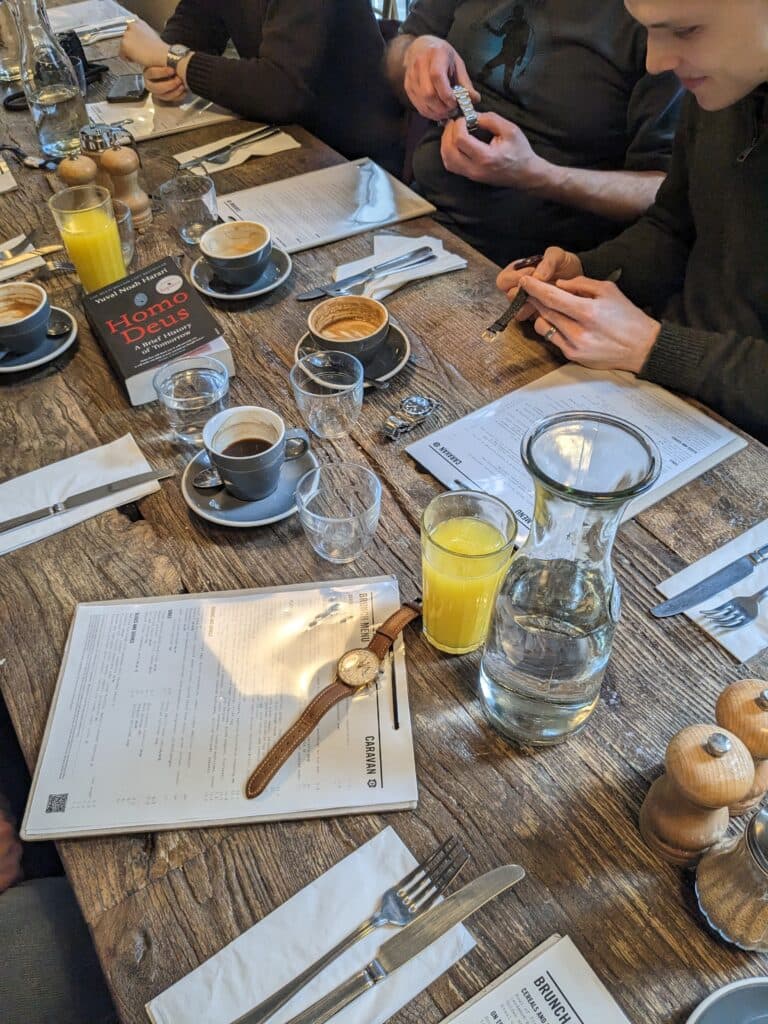 a Brunch Meetup with people looking at watches, coffee and juice on the table as well as vintage watches