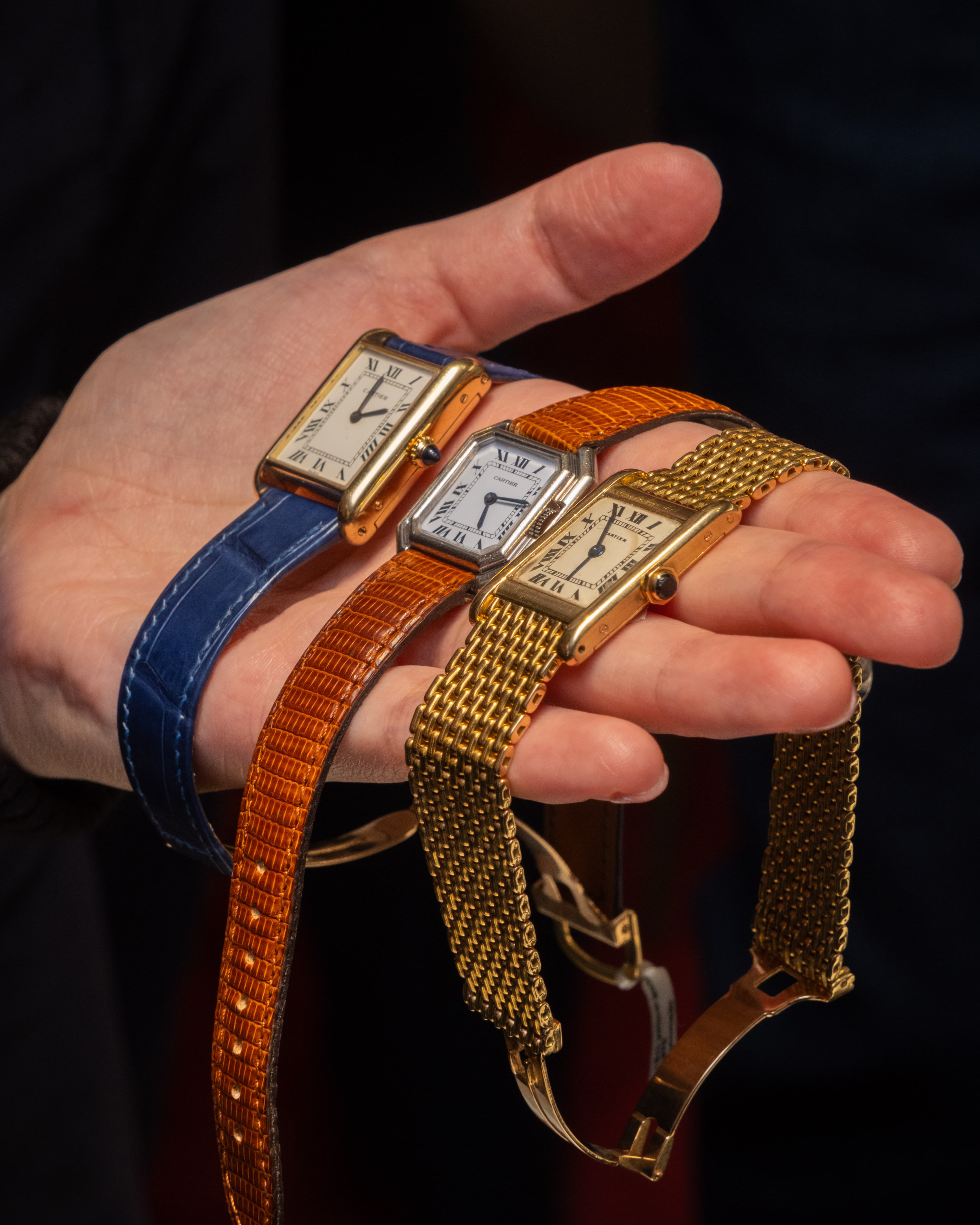 three gols vintage cartier watches on different staps on the palm of a hand at Somlo London
