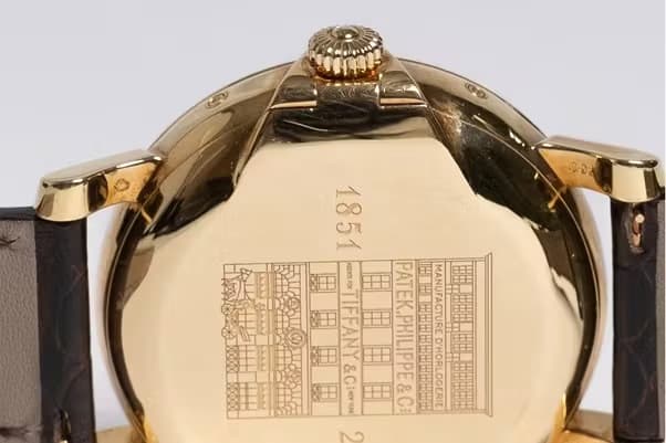 The engraved caseback of the T150 watch showing an old storefront with Tiffany and Patek Philippe signs.