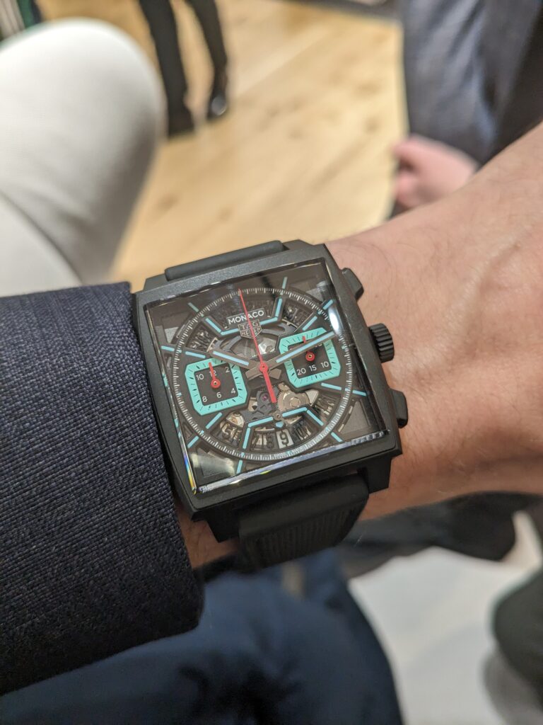 square tag heuer monaco watch with dark grey case, skeleton dial with light blue and white highlights